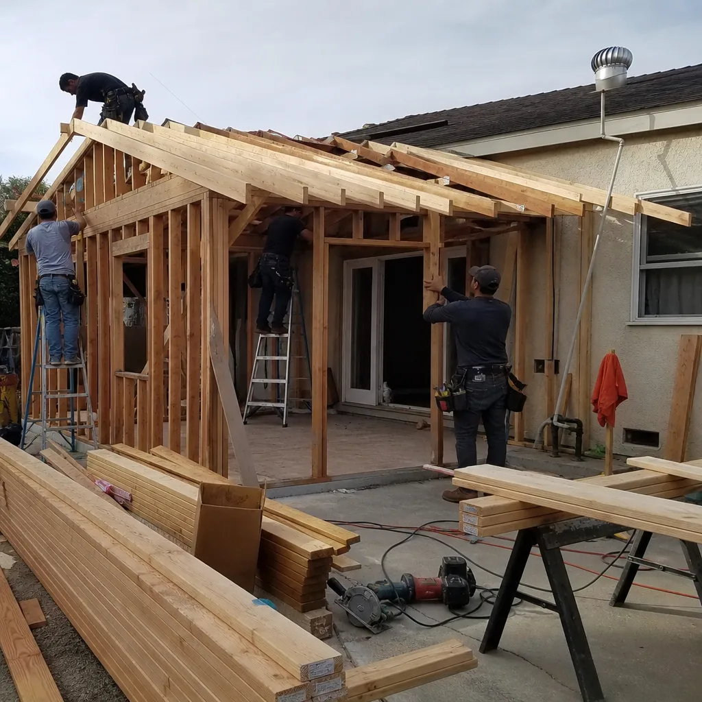Contractors building a wooden home addition frame on a construction site